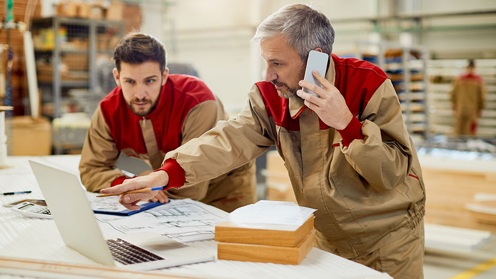 un artisan au téléphone qui peaufine un projet